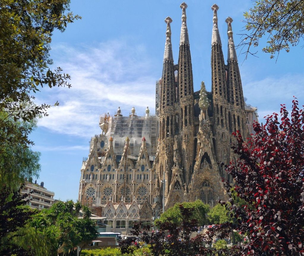 La Sagrada Familia, con sus fachadas intrincadas y altas torres, mezcla de formas góticas y Art Nouveau curvilíneo.